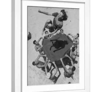Teenaged Boys Using Blanket to Toss Their Friend, Norma Baker, Into the Air on the Beach - White Framed Art Print Wall Art, 12x16